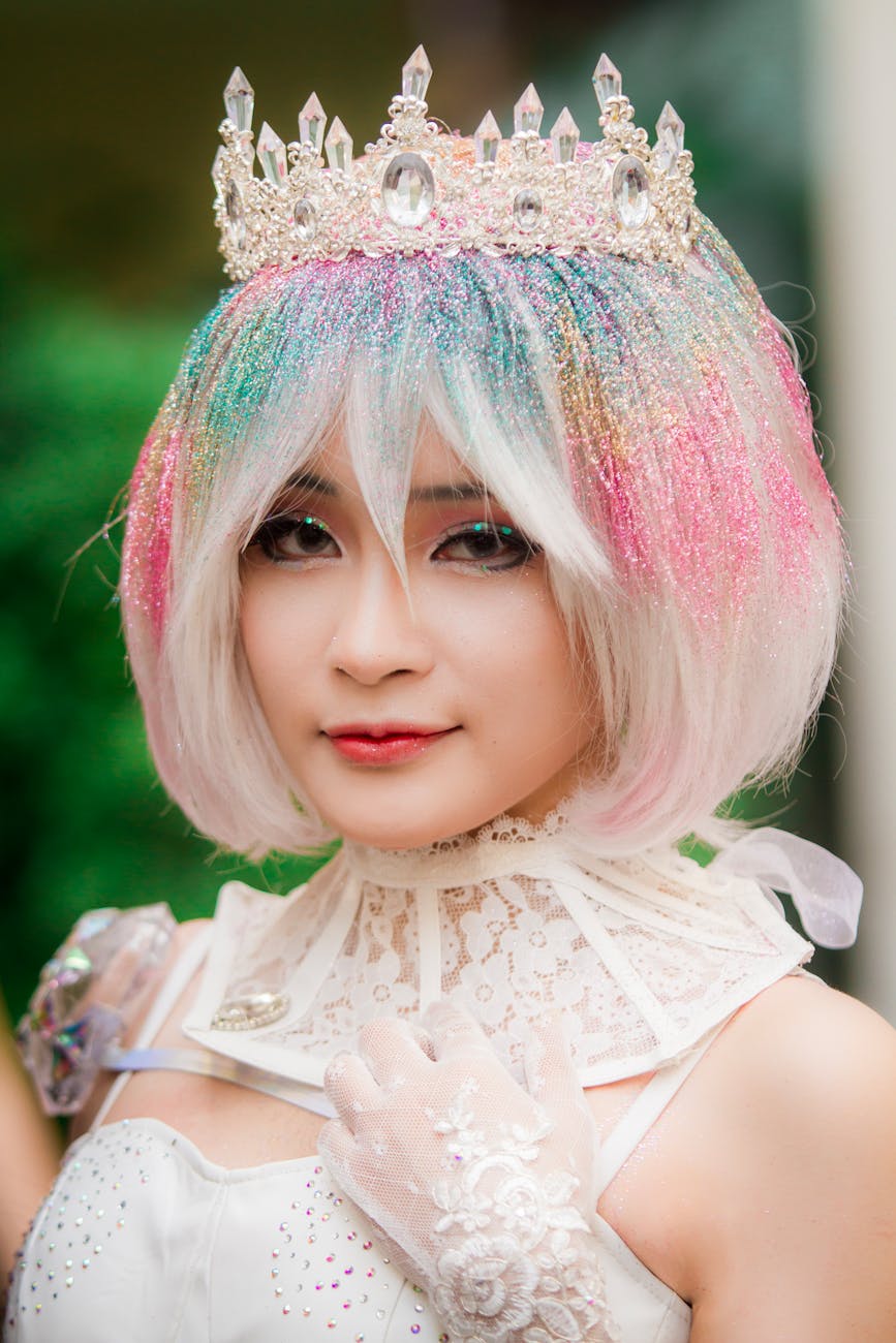 Colorful portrait of a woman in cosplay with glitter hair and jeweled crown, embodying fantasy elegance.