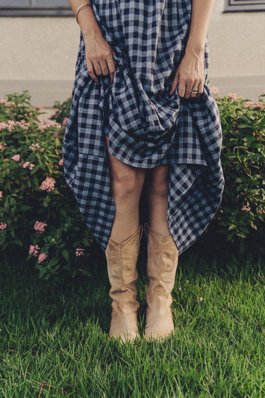 Fashionable woman in cowboy boots and checkered dress outdoors in Texas.
