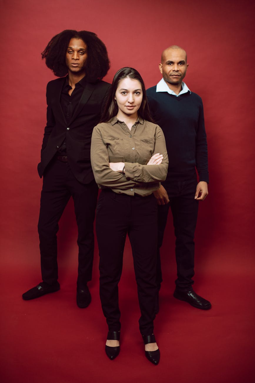 Portrait of diverse professionals standing against red background in studio. [pexels]