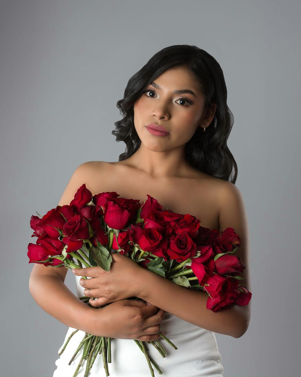 Stunning portrait of a woman holding red roses, captured in a professional studio setting.