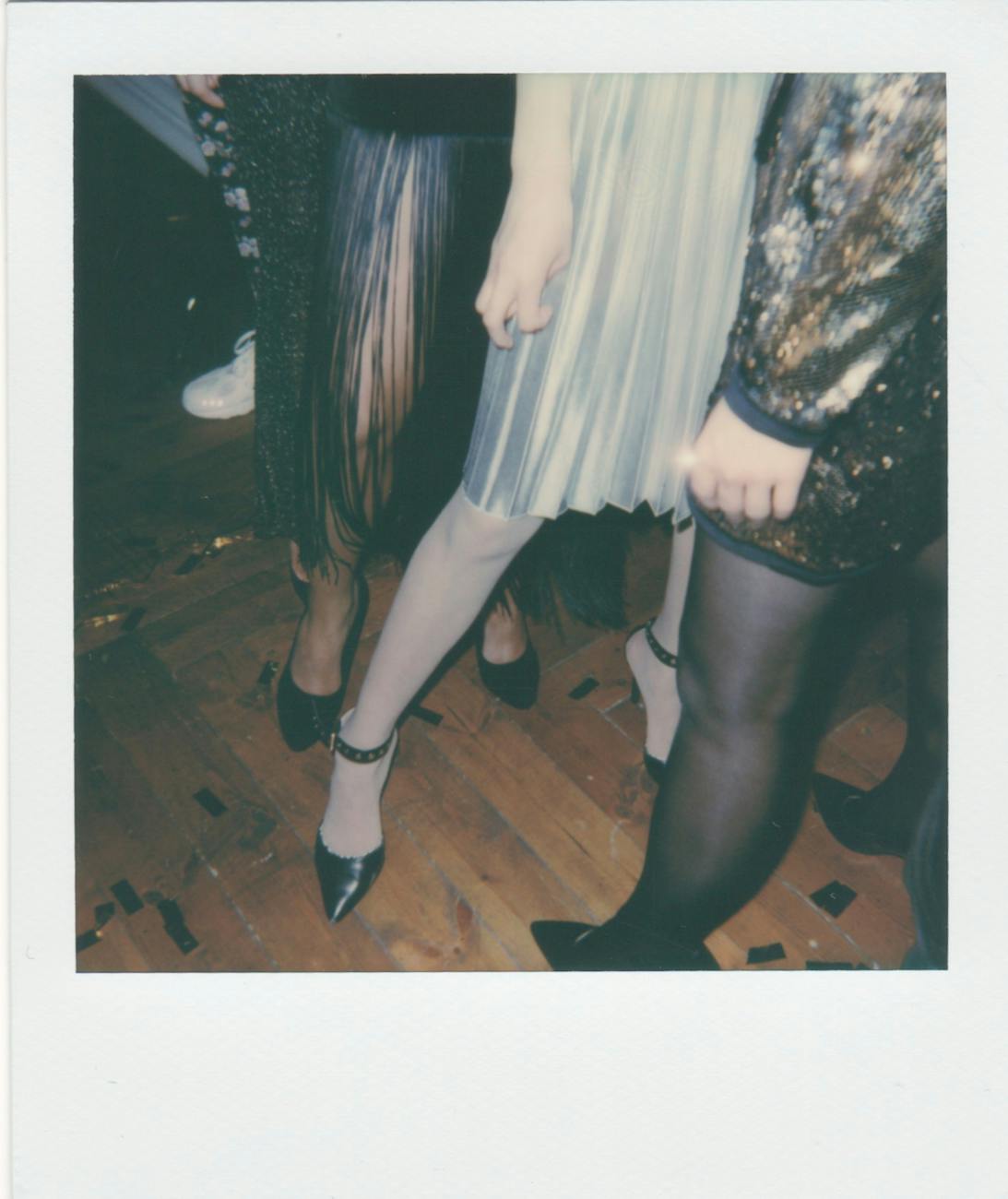 Stylish women in chic outfits and heels at a lively indoor party. [pexels]